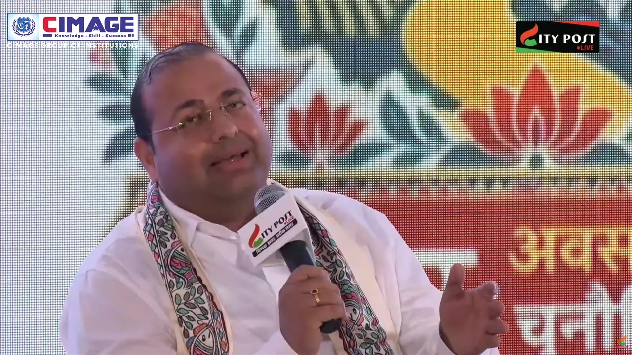 A male speaker holding a microphone while speaking during a panel session.